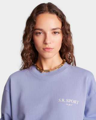 Woman with wavy brown hair in a Wimbledon Crewneck - Colony/Cream sweatshirt made from USA grown cotton, paired with a gold necklace, facing forward.