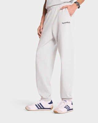 Individual wearing Serif Logo Sweatpant in Heather Gray/Navy, crafted in the USA, teamed with white sneakers featuring navy stripes.