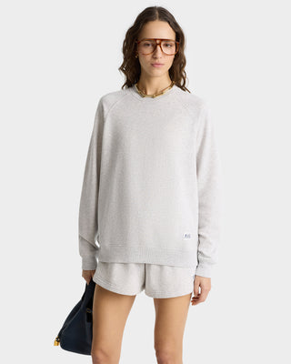 Wearing the SR Runner Soft Crewneck in Heather Gray with shorts and holding a black bag, this person stands against a plain background.
