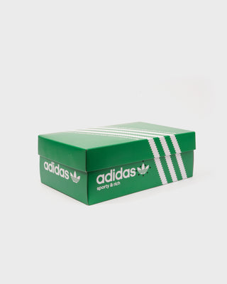 Grey Adistar Cushion shoe box by Adidas featuring white stripes and sporty & rich text, highlighting the comfort and innovative Adiprene midsole, displayed on a white background.