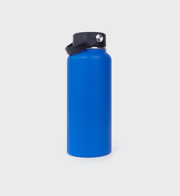 back of blue stainless steel water bottle with gold 'Sporty & Rich Health & Wellness Club' text on the side, featuring a black screw-on lid with a metal accent."