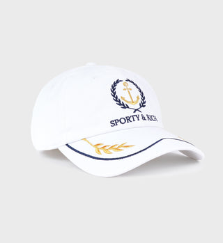The Yacht Hat in White/Metallic Gold/Dark Navy features anchor and laurel embroidery, Sporty & Rich text, a gold leaf brim accent, and an adjustable closure for a perfect fit.