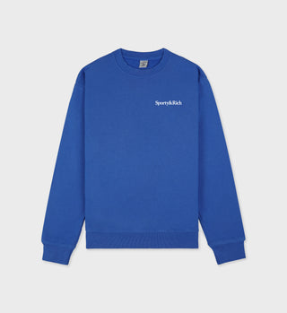 Royal blue crewneck sweatshirt with white 'Sporty & Rich' text on the left chest, featuring ribbed hem and cuffs.