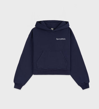The Health is Wealth Cropped Hoodie in navy features a front pocket, Sporty & Rich text on the left chest, and is made from pre-shrunk, USA-grown cotton for lasting comfort.