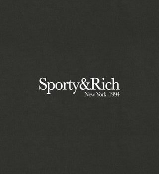 Close up of logo 'Sporty & Rich' written in white on a faded black short sleeve t-shirt