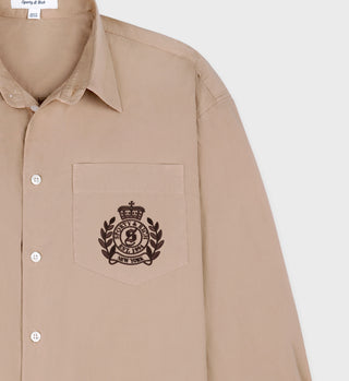 Light tan H&W Crest Oversized Shirt with chocolate embroidered crest on the chest pocket, offering an oversized fit for ultimate comfort, made in Portugal.