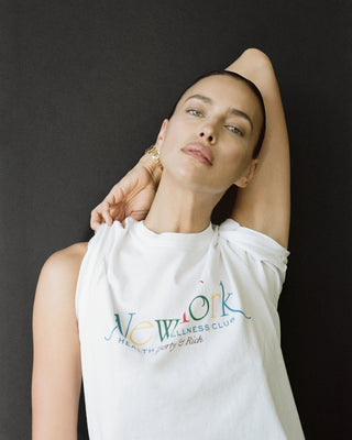 Model poses with an arm behind their head, wearing the NY 94 T-Shirt in White/Multi, crafted from USA-grown cotton, against a dark backdrop.