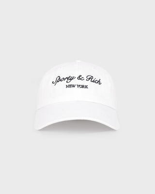 The Syracuse Hat - White/Navy is a white cotton twill dad hat with Sporty & Rich NEW YORK embroidered in navy on the front, featuring an adjustable closure and shown against a plain background.