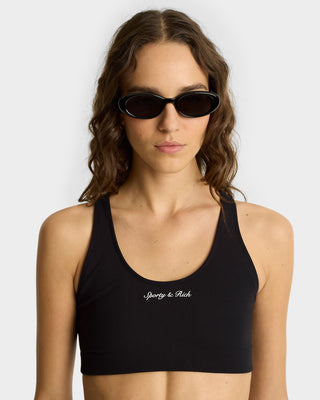 Woman in black sunglasses wearing the Syracuse Biker Shorts in Black/White, paired with a Sporty & Rich sports bra for a chic luxury activewear look, facing forward.