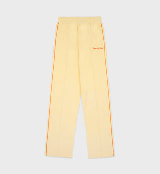 Almond sweatpants with pomodoro side stripes, made from 100% cotton and featuring Sports & Riches text near the waistband. These stylish New Serif Terry Track Pants blend comfort with flair, crafted in Portugal.