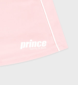 Close-up of the Prince Sporty Court Skirt in baby pink with a white elastic waistband, bold Sporty & Rich text, and a crisp white stripe detail.